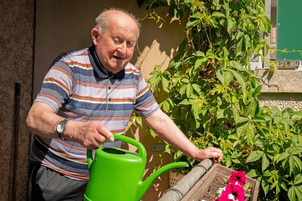 Bewohner auf seinem Balkon, bei der Pflanezenpflege